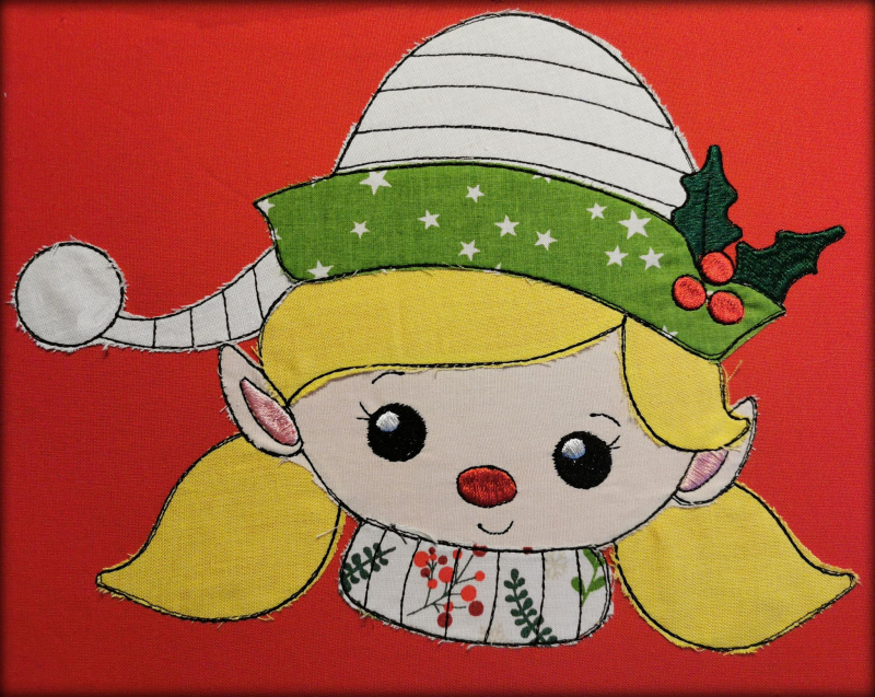 Stickdatei Set Christmas Faces Doodle-Applikationen. Foto von Applikation eines Mädchenkopfes mit Mütze, aufgebracht auf roten Stoff.