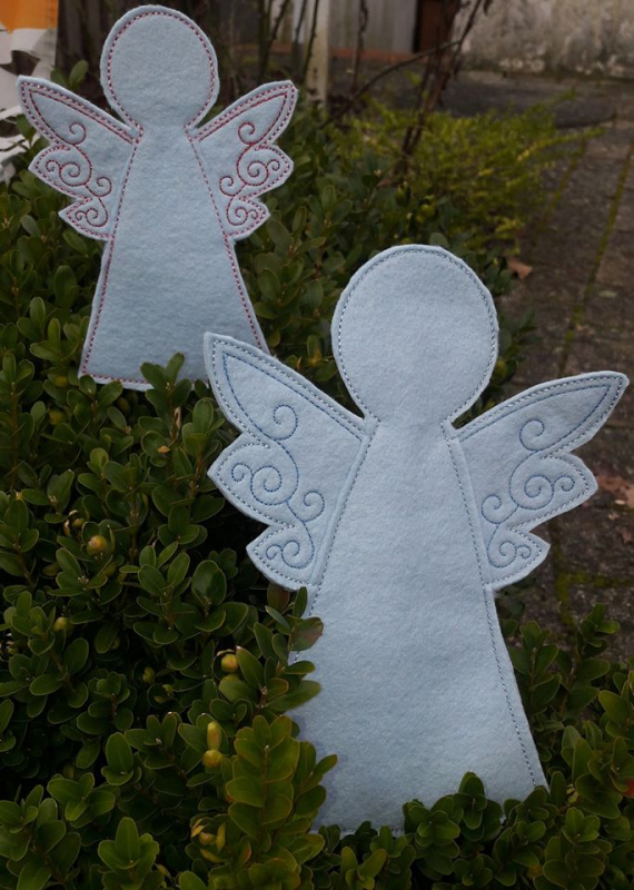 Stickdatei Set ITH Stabdateien mit Engel, Stern und Christbaum, Foto mit 2 Engeln in Buchsbaumbusch. Weißer Filz, verziert mit spiraligen Mustern der Flügel, einmal blau, einmal rosa.