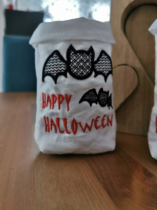 Stickdatei Set ITH Lichtbeutel Halloween (13x18 Rahmen) plus Einzelmotive, Foto mit Lichtbeutel, auf Tisch präsentiert. Heller Stoffuntergrund, 1 große und eine kleine Fledermaus in schwarz als Motiv, unten roter Schriftzug "HAPPY HALLOWEEN". Stickdatei Set ITH Lichtbeutel Halloween (13x18 Rahmen) plus Einzelmotive, Foto mit Lichtbeutel, auf Tisch präsentiert. Heller Stoffuntergrund, 1 große und eine kleine Fledermaus in schwarz als Motiv, unten roter Schriftzug "HAPPY HALLOWEEN".