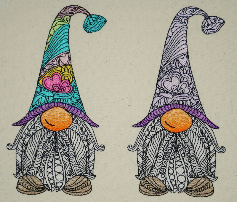 Stickdatei Gnom (div. Größen) Vollstick inkl. ITH Anhänger, Foto zeigt 2 Gnome auf hellem Stoff. Filigrane Bestickung der Innenflächen, teilweise unterschiedliche Garnfarben (eine Mütze dezent, 1 Mütze bunt).