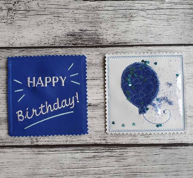 Stickdatei Set ITH Geburtstagskarten (10x10 u. 13x18), Foto mit 2 quadratischen Karten auf Holzuntergrund. 1 mal dunkelblau, Schriftzug "HAPPY Birthday", Strahlen/Strich; 1 mal mit transparenter Folie auf hellem luftballonbesticktem Untergrund, dazwischen