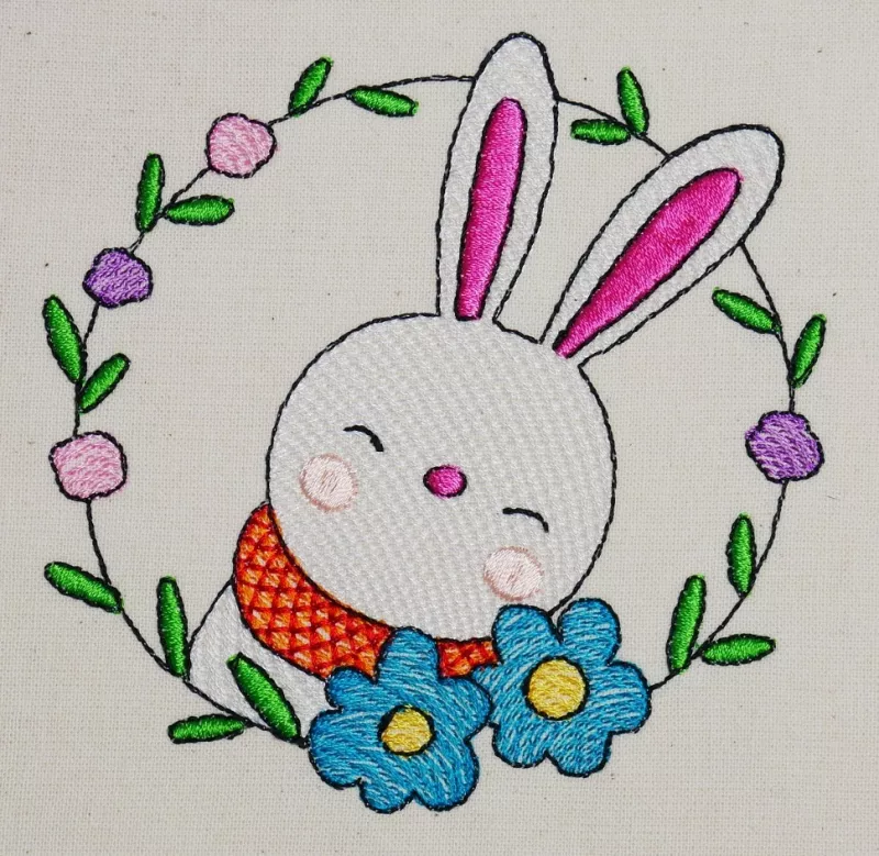 Osterhase mit floralem Kranz ausgestickt auf Baumwolle.