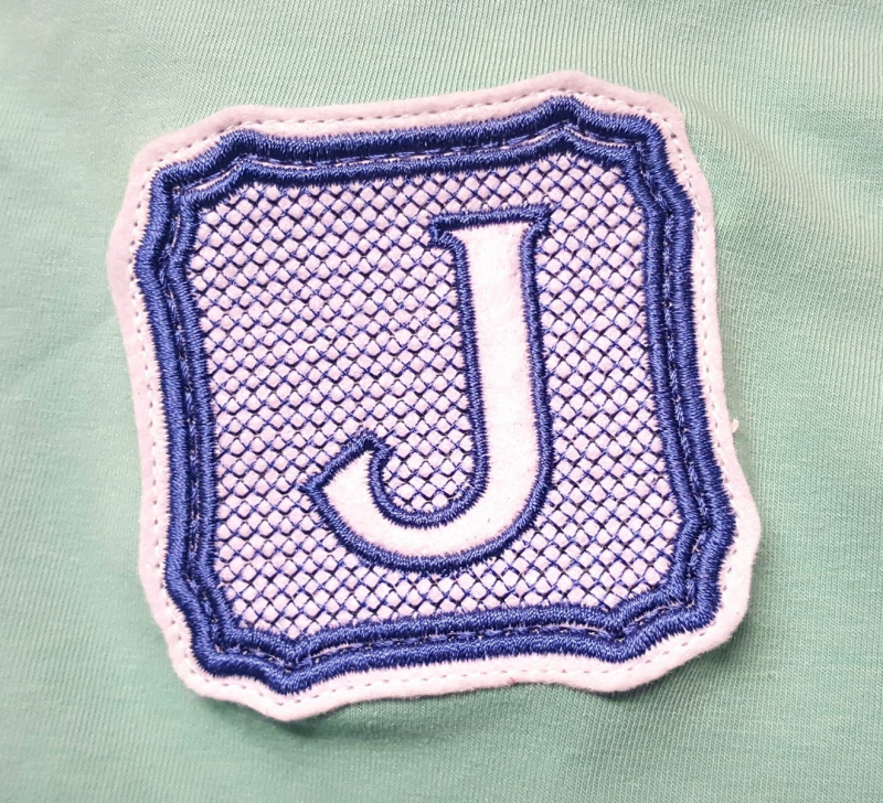Stickdatei Set Monogramme Elegant geeignet für Frottierwaren, Foto mit Buchstabe "J" in Umrahmung, der auf schilffarbenem Jerseystoff aufgenäht ist. Monogrammfarben sind lila und rosa. Stickdatei Set Monogramme Elegant geeignet für Frottierwaren, Foto mit Buchstabe "J" in Umrahmung, der auf schilffarbenem Jerseystoff aufgenäht ist. Monogrammfarben sind lila und rosa.