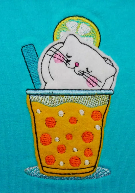 Stickdatei Set Hello Summer Cat Doodle Applikation inkl. ITH Anhänger, Foto zeigt Applikation auf türkisem Stoff. Katze, beigefarben im Glas mit Limettenscheibe und grünem Strohhalm, badend in orange-gelbem Drink.