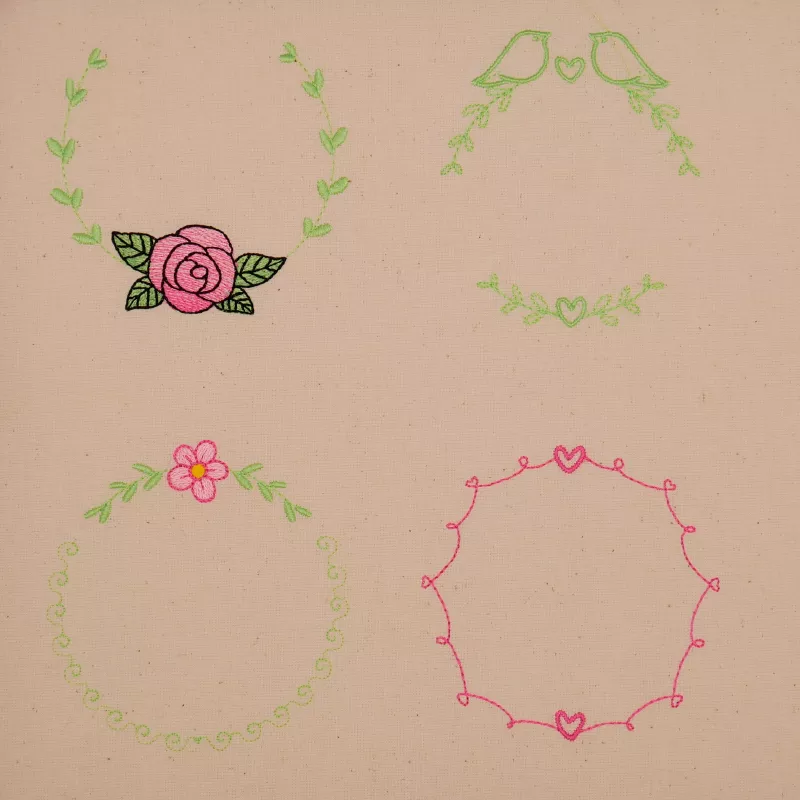 Stickdatei Set florale Rahmen + Schriftzüge, Foto mit hellem Stoff, bestickt mit 4 Designs in Rundoptik. 1 mal ausgestickte Blüte mit Blättern, flankiert von 2 Blattzweigen; 1 mal 3 Blattzweige mit Herzen und Vögeln; 1 mal Blüte mit Blattzweigen und Schnö