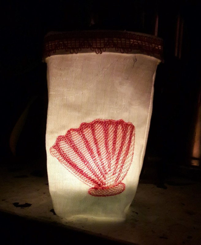 Stickdatei Set ITH Lichtbeutel Unterwasserwelt, Foto mit hell erleuchtetem Lichtbeutel in dunklem Raum. Auf hellem Stoff orangerote Bestickung mit Muschel. Stickdatei Set ITH Lichtbeutel Unterwasserwelt, Foto mit hell erleuchtetem Lichtbeutel in dunklem Raum. Auf hellem Stoff orangerote Bestickung mit Muschel.