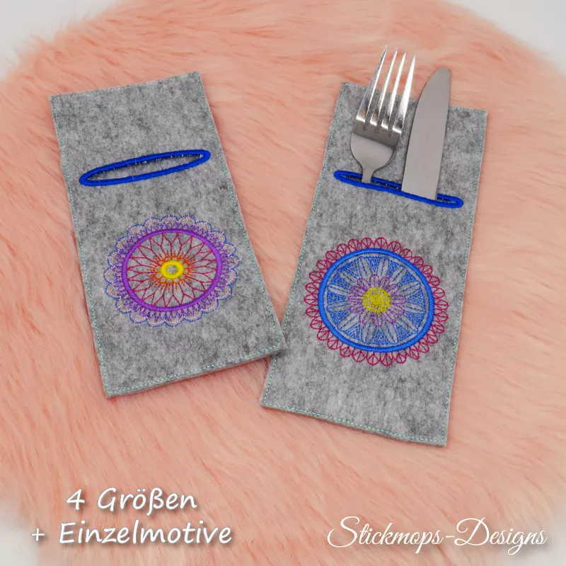 Stickdatei Set Mandala-Bestecktaschen + Einzelmotive, Foto mit 2 auf orangefarbenem Fell nebeneinander drapierten Bestecktaschen, die rechte mit Gabel und Messer eingesteckt. Mittelgrauer Filz, Hochkantformat, dunkelblau umstickte Einstecköffnung