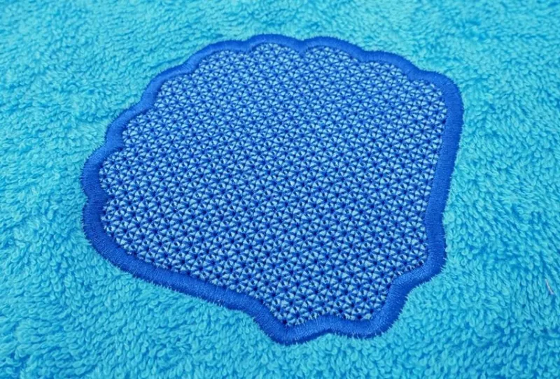 Stickdatei Set Maritime Handtuch Motive Embossed 10x10, Foto zeigt mittelblauen  Frotteestoff mit dunkelblauer Bestickung: Muschelumrandung mit gemusterter Füllfläche.