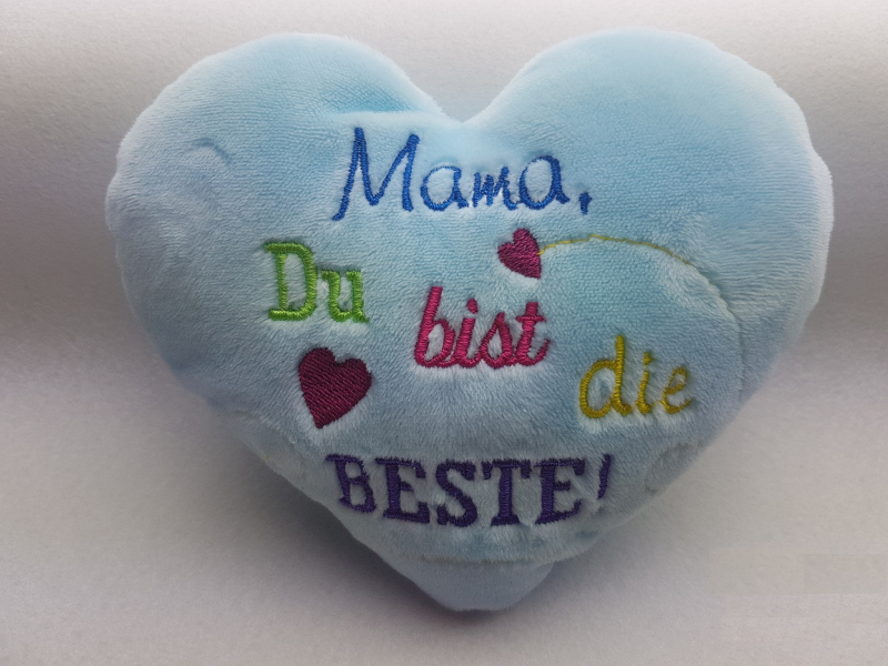 Stickdatei Set Danke Sprüche, Foto mit hellblauem Plüschherz: Bunter Schriftzug "Mama, du bist die Beste!". Mit roten Herzchen.
