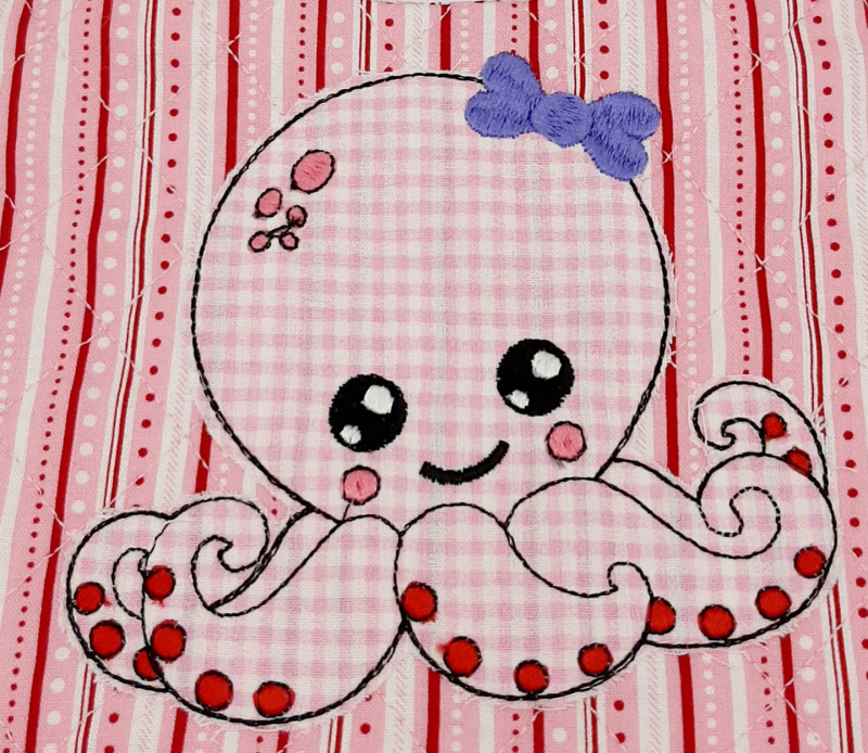 Stickdatei Octopus Applikation für Mädchen, Foto zeigt Oktopus aus rosa-weiß kariertem und besticktem Stoff auf rot-rosa-weiß gestreiftem/gepunktetem Stoff. Dicke lila Stickschleife am Kopf. Stickdatei Octopus Applikation für Mädchen, Foto zeigt Oktopus aus rosa-weiß kariertem und besticktem Stoff auf rot-rosa-weiß gestreiftem/gepunktetem Stoff. Dicke lila Stickschleife am Kopf.