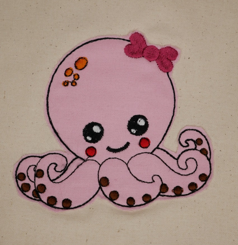 Stickdatei Set Octopus Applikation für Junge & Mädchen, Foto zeigt bestickte Oktopus-Applikation aus rosa Stoff auf hellem Stoffuntergrund. Dicke Stickschleife am Kopf.
