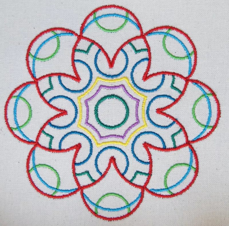 Stickdatei-Set Ornamente Dream 10 x 10 cm, Foto mit bogenartigem Blütenornament, eher grobe Musterausfertigung auf hellem Stoff. 7 bunte Garne.