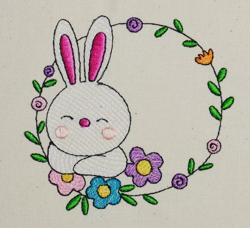 Osterhase mit floralem Kranz ausgestickt auf Baumwolle.