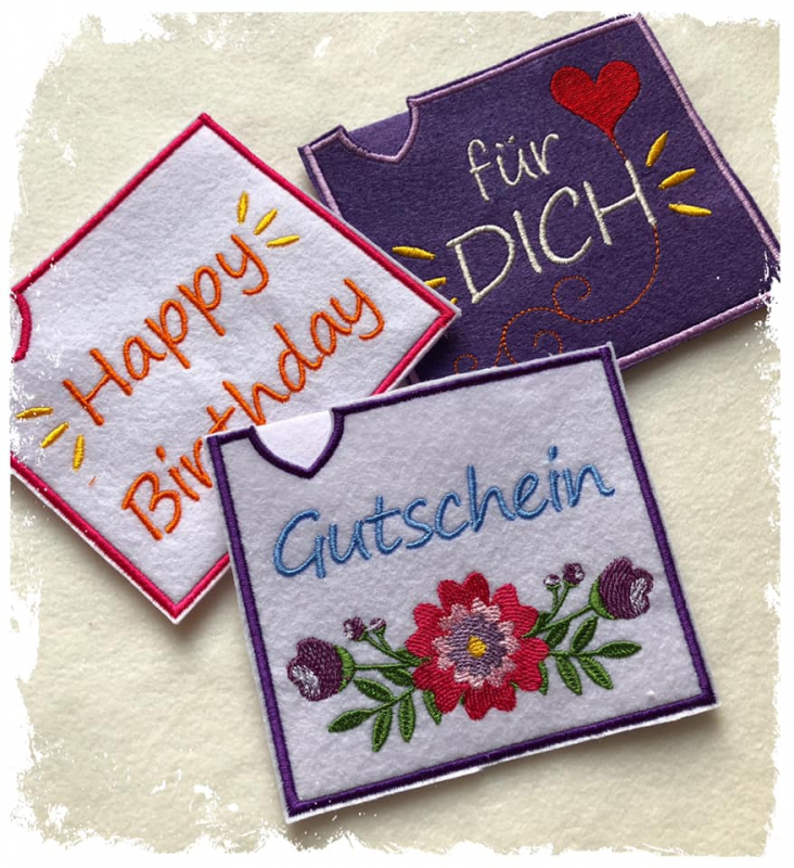 Stickdatei Set ITH Motivhüllen für viele Anlässe für Schokolade, Gutscheine u.a., Foto zeigt 3 rechteckige Hüllen. 1 mal hell, Bestickung: "Happy Birthday" mit Strahen; 1 mal lila, Bestickung: "für dich" mit Herz/Schnörkeln; 1 mal hell, Bestickung: "Gutsc