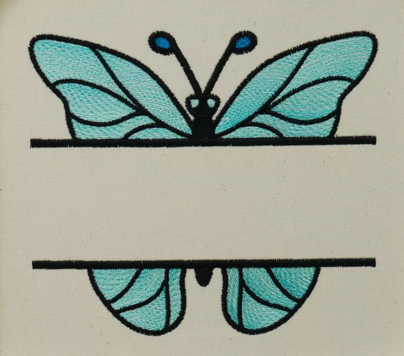 Stickdatei Split Butterfly 1, Foto mit türkis-schwarzem Schmetterling auf hellem Stoff. Davor mittig quer eine freie Fläche für Schriftzüge.
