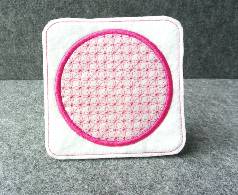 Stickdatei Set ITH Mug Rug 10. Quadratischer weißer Filzstoff, der am Rand pink abgesteppt ist. Mittig rundes Emblem mit kreisrundem pinkem filigranem Blütenornament, dessen Rand mit Garn derselben Farbe dick umrandet gestickt ist. Stickdatei Set ITH Mug Rug 10. Quadratischer weißer Filzstoff, der am Rand pink abgesteppt ist. Mittig rundes Emblem mit kreisrundem pinkem filigranem Blütenornament, dessen Rand mit Garn derselben Farbe dick umrandet gestickt ist.