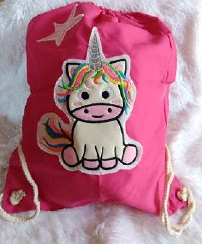 Stickdatei Sweet Unicorn (div. Rahmengrößen), Foto zeigt pinken Sportbeutel mit Stern und Einhorn-Applikation. Sitzendes Einhorn, bunte Mähne, bunter Schweif.