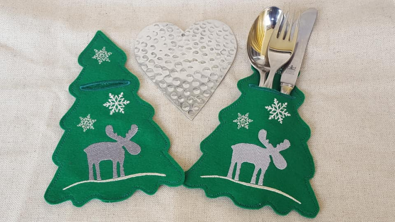 Stickdatei Set weihnachtliche ITH Bestecktaschen, Foto zeigt 2 Taschen, eine besteckgefüllte. Grüne Taschen in Weihnachtsbaumumriss, grau-weiße Bestickung mit Sternen und Elch. Stickdatei Set weihnachtliche ITH Bestecktaschen, Foto zeigt 2 Taschen, eine besteckgefüllte. Grüne Taschen in Weihnachtsbaumumriss, grau-weiße Bestickung mit Sternen und Elch.