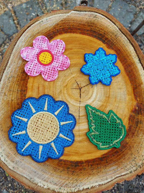 Stickdatei Set FSL Gnome rund um das Jahr + ITH Anhänger, Foto zeigt 4 ausgestickte Einzelmotive, alle in netzartiger Optik gefertigt. Blüte in rosa-weiß mit rot-gelbem Zentrum; Stern in 2 kontrastigen Blautönen; gelbe Sonne auf wellig-rundem Untergrund i Stickdatei Set FSL Gnome rund um das Jahr + ITH Anhänger, Foto zeigt 4 ausgestickte Einzelmotive, alle in netzartiger Optik gefertigt. Blüte in rosa-weiß mit rot-gelbem Zentrum; Stern in 2 kontrastigen Blautönen; gelbe Sonne auf wellig-rundem Untergrund i