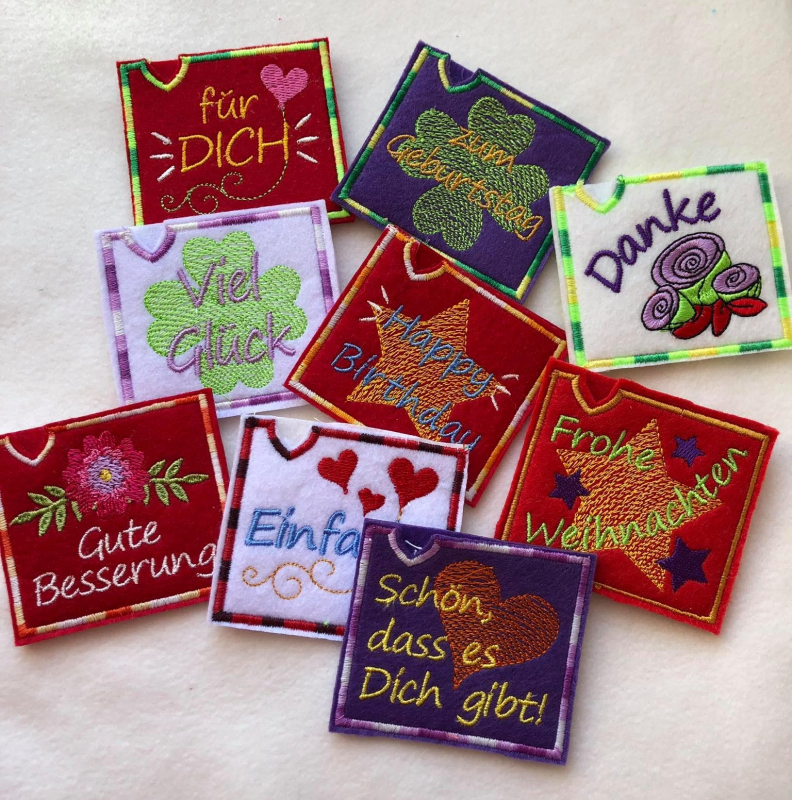 Stickdatei Set Mini ITH Schoko- und Gutscheinhüllen (10x10 Rahmen) für viele Anlässe, Foto zeigt 9 quadratische Filzüllen, Grundfarben rot, lila, crème, rosa, rot. Bestickt mit Glücksklee, Herz, Stern oder Blüte/n. Mit Aufschrift "für DICH", "zum Geburtst