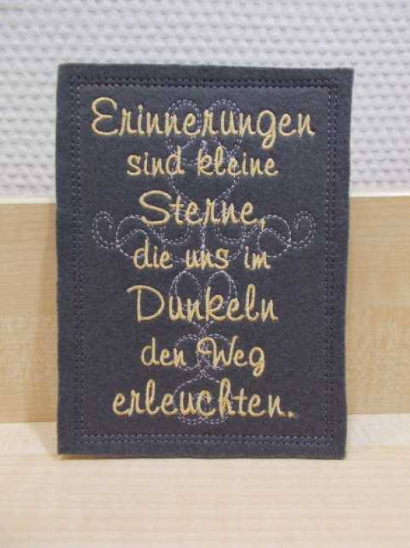 Stickdatei Set ITH Glückwunschkarten inkl. Abwandlung zur Geschenktasche (div. Rahmengr.), Foto zeigt Hochkant-Karte aus auberginefarbenem Filz. Filigrane Verzierung mittig, davor Schriftzug über ganze Karte: "Erinnerungen sind kleine Sterne, die uns im D