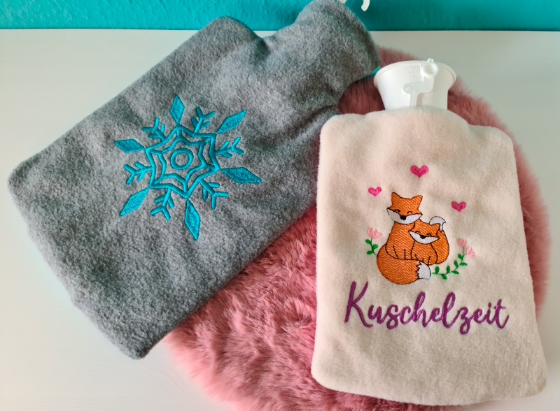 Stickdatei XXL Set ITH Wärmflaschenhüllen mit 24 Designs, Foto zeigt 2 Hüllen aus Flauschstoff. Eine dunkelgrau, mit Auszug für Flaschenhals, türkisblauer Schneestern. Eine hell, ohne Auszug, Fuchs mit Kind, Herzchen, Blütenranke, Schriftzug "Kuschelzeit" Stickdatei XXL Set ITH Wärmflaschenhüllen mit 24 Designs, Foto zeigt 2 Hüllen aus Flauschstoff. Eine dunkelgrau, mit Auszug für Flaschenhals, türkisblauer Schneestern. Eine hell, ohne Auszug, Fuchs mit Kind, Herzchen, Blütenranke, Schriftzug "Kuschelzeit"