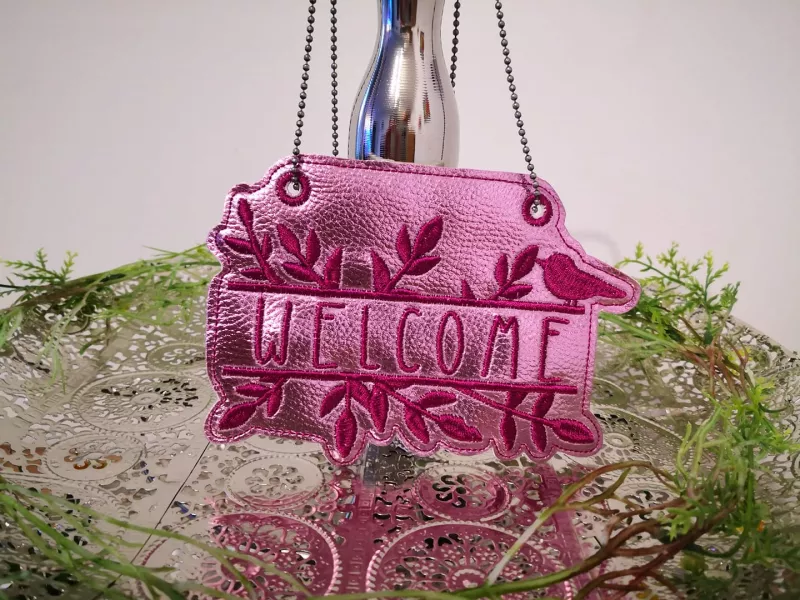 Stickdatei Set ITH Schilder, Stabdeko & Schriftzüge Home Sweet Home Anhänger Welcome aus rosa Kunstleder mit lila Stick
